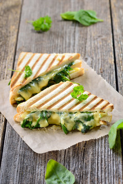 Im Kontaktgrill gepresstes italienisches Panini mit jungem Blattspinat, Zwiebeln  und Käse - Pressed and toasted double panini with spinach, onions and cheese served on sandwich paper