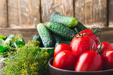 Ripe organic cucumbers and tomatoes on rustic wooden table