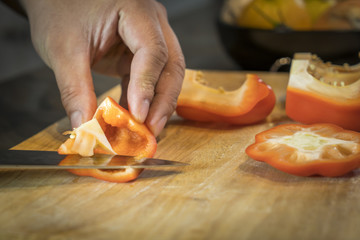 Chef cutting red bell pepper on wooden broad
