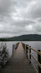 Wood pier leading to a cold lake with mountains in the background