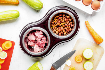Dogfood set with cut vegetables and knife on table background to