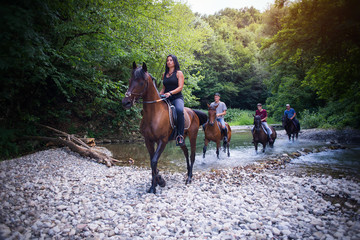 Group of friends riding horses on the river