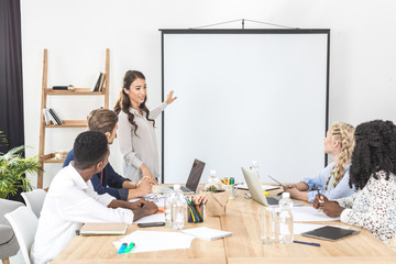 young asian businesswoman pointing at projection screen while making presentation in office