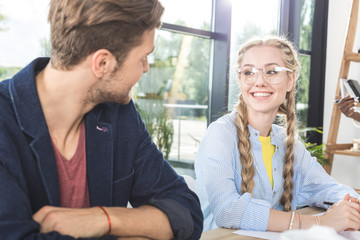 portrait of smiling business colleagues having conversation while sitting at table in office