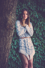 Fototapeta premium Female leaning against green leaf wall next to the tree