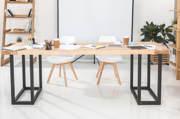 empty business workplace with chairs, projection screen and table with office supplies on it