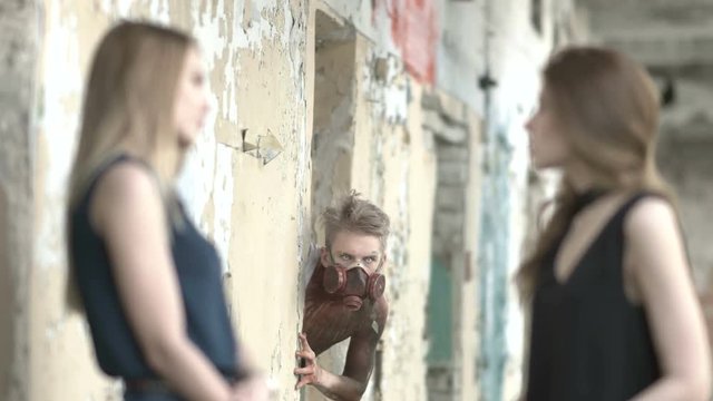 Girls talk near an abandoned house and maniac watches them