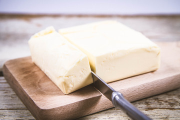 Butter on a wooden chopping board  cut with a knife