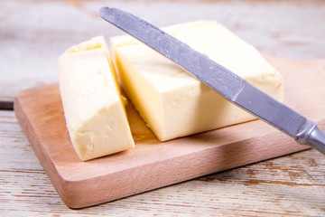 Butter on a wooden chopping board  cut with a knife
