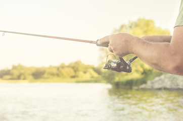 Fisherman's hands with spinning on the background of water