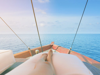 Private boat trip on open sea. Image shows legs of a woman lying on a thick and comfortable cushion...