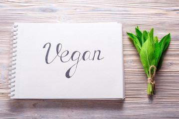 Hand written letters Vegan in notebook  on wood background