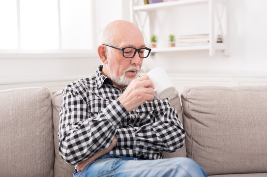 Senior Man Having Cup Of Coffee In Living Room