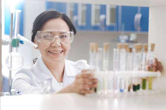 Happy positive chemist standing near the test tube rack