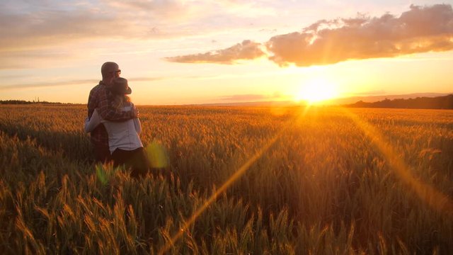 Young couple watching sunset in a barley field