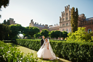 Obraz premium Attractive wedding couple posing in the garden of a majestic mansion.