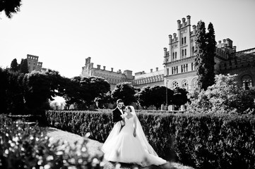 Obraz premium Attractive wedding couple posing in the garden of a majestic mansion. Black and white photo.