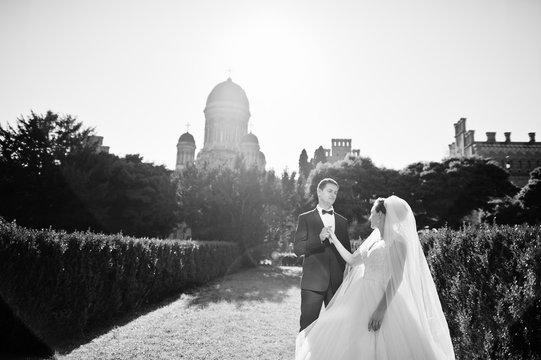 Attractive wedding couple posing in the garden of a majestic mansion. Black and white photo.
