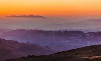 Sunset sky above layers of foggy mountains