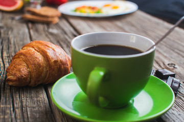 Breakfast with coffee and croissants on wooden vintage table