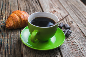 Breakfast with coffee and croissants on wooden vintage table