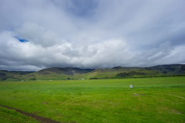 Fototapeta na wymiar Iceland - Wide green landscape and mountains with clouds