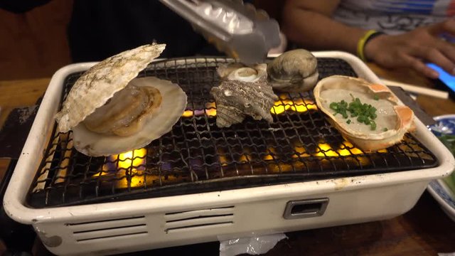 Japanese seafood barbecue , sea shell and clam shell BBQ grilled on fire from butane gas stove ,very sweet and delicious
