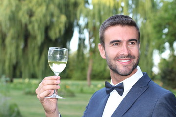 Striking man drinking white wine outdoors