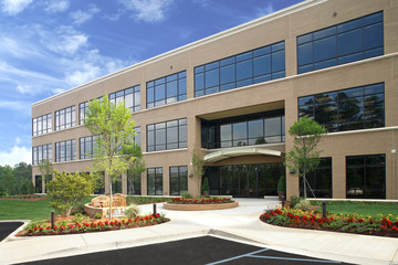 Generic Brick Office Building Exterior with lush Landscaping trees and flowers - Powered by Adobe