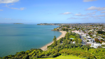Fototapeta na wymiar Aerial view on sunny beach with residential suburb on the background. Auckland, New Zealand.