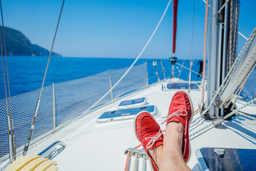 A pair of man legs in topsiders on white yacht deck. Yachting