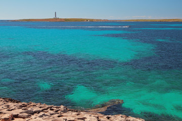 Sea gulf and island with beacon. Punta Prima, Minorca, Spain