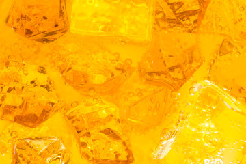 Close-up of ice cubes in drink or orange juice