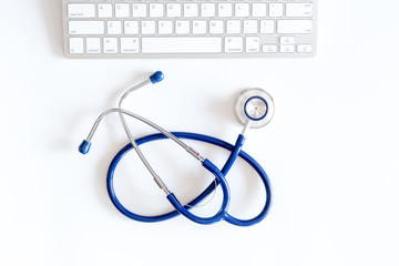 Doctor's work table in clinic. Stethoscope and keyboard on white background top view copyspace