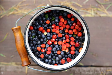 Blueberries and strawberries on an old wooden table in the bucket