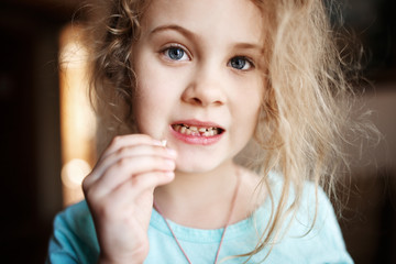Smiling girl holding missing milk tooth, close up photo.