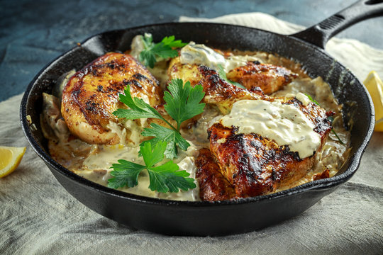 Creamy chicken fellets supremes in mushroom sauce with parsley In rustic cast iron skillet.