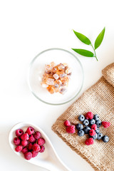 Making summer preserve. Raspberry, blueberry and sugar on white background top view copyspace