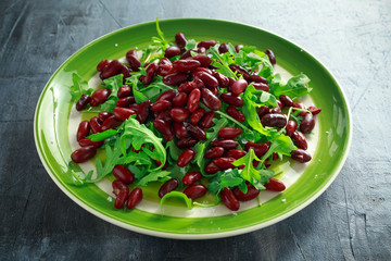 Red beans and wild rocket healthy salad in a green plate