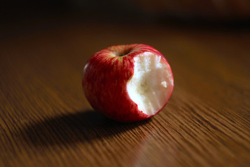 Partially Eaten Red Apple On A Wooden Table