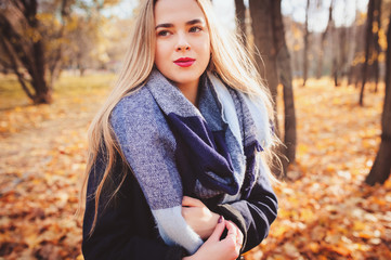 autumn outdoor casual portrait of young beautiful woman walking in park in warm fashion outfit, weraing coat and scarf