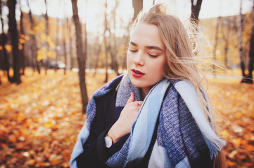 autumn outdoor casual portrait of young beautiful woman walking in park in warm fashion outfit, weraing coat and scarf