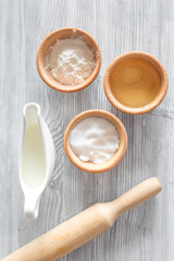 Put the dough. Flour, salt, mik, oil, rolling pin on light wooden table background top view
