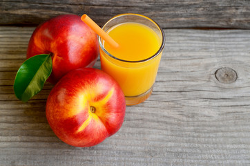 Fresh ripe organic nectarines and a glass of juice on old wooden table.Nectarine juice.Peach juice.Diet,healthy food,raw food concept.Selective focus.