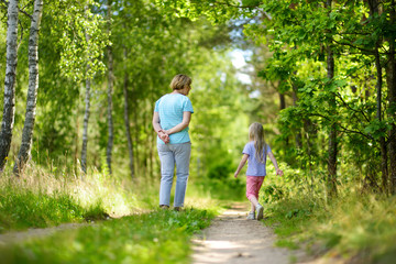 Obraz premium Cute little girl hiking in a forest with her grandmother on beautiful summer day