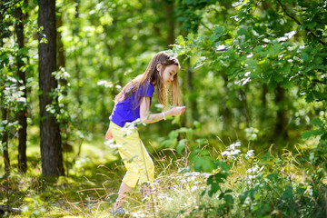 Cute little girl having fun during forest hike on beautiful summer day