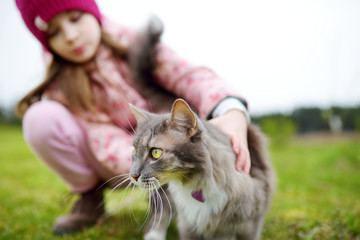 Cute little girl with her pet cat on autumn day