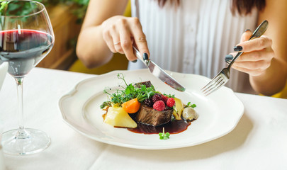 woman eating beef steak with berry sauce