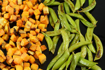 Roasted snap beans and cubed yams sprinkled with olive oil on baking pan