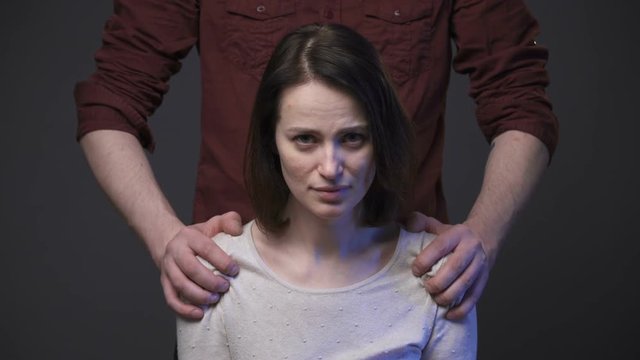 Family abuse, man's hands keeping woman's shoulders